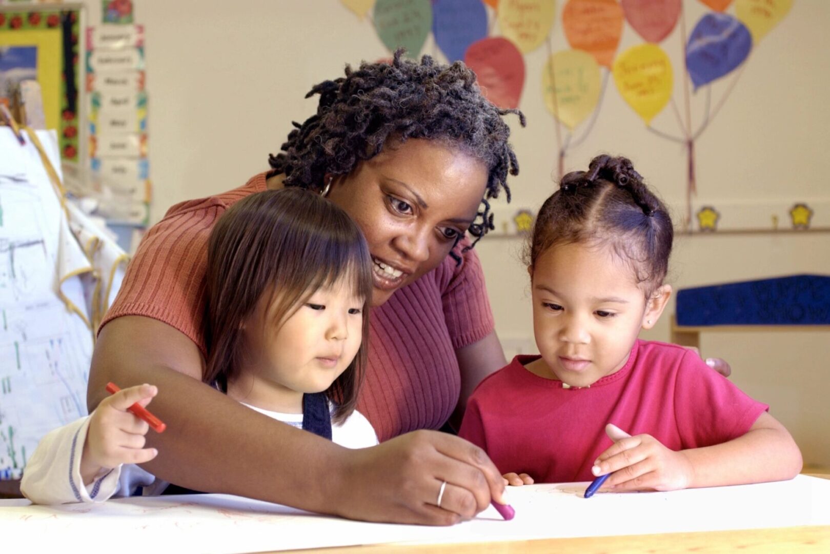 A woman and two children drawing on paper.